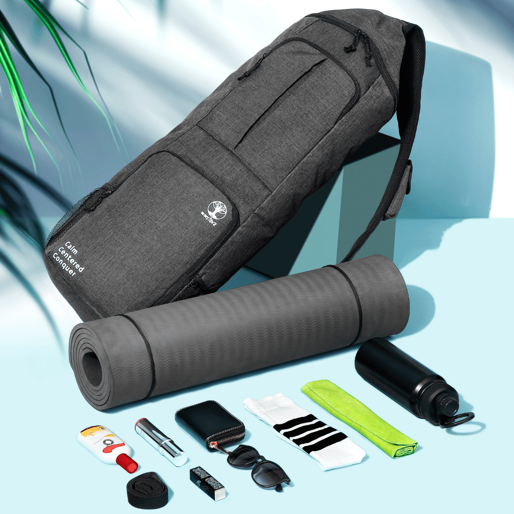 Black Warrior2 yoga mat backpack displayed upright next to a rolled yoga mat, water bottle, towel, socks, and other workout accessories.