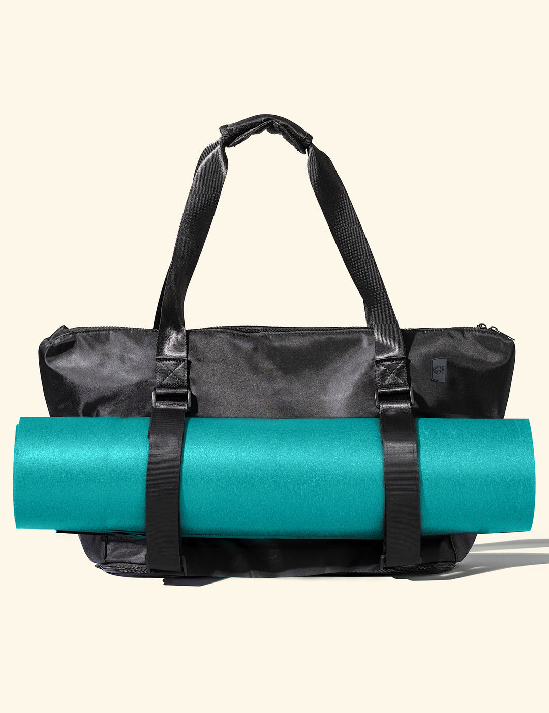 Black yoga work tote bag with a teal yoga mat inside on a beige background