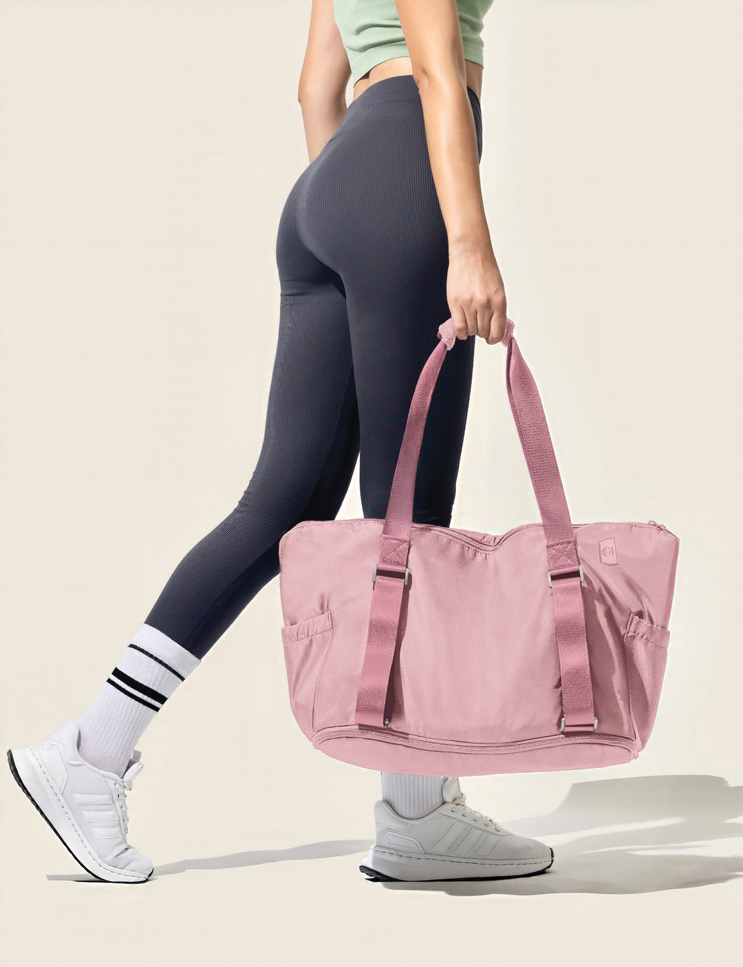 fit girl holding a warrior2 pink yoga gym bag with a neutral background