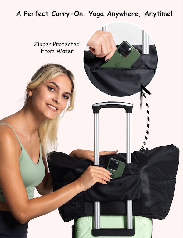 Woman placing phone into black Warrior2 yoga mat tote bag for travel with water-protected zipper, secured on top of a mint green suitcase handle.