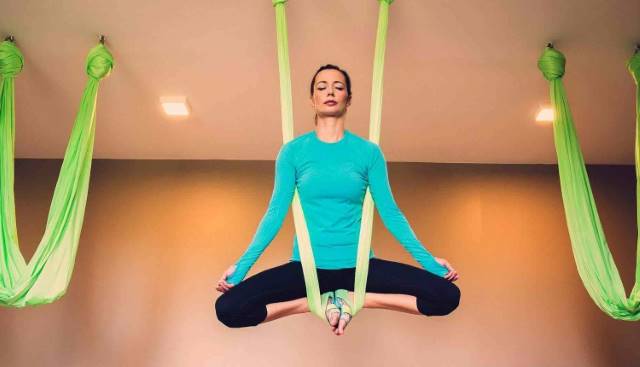 woman in blue shirt is aerial yoga safe