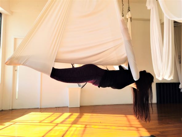 aerial yoga vampire pose sunset studio window white yoga hammock