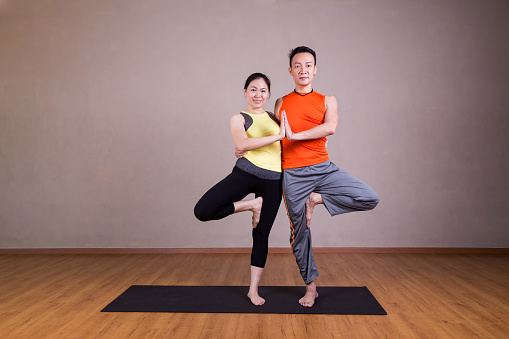 Couple perform Double Tree yoga partner pose in studio