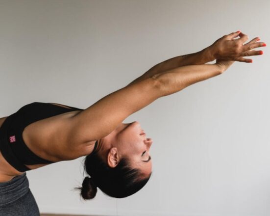 woman arms up leaning back differences between Yin Yoga and Restorative Yoga