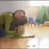 woman doing restorative yoga sitting resting on pillow in yoga studio