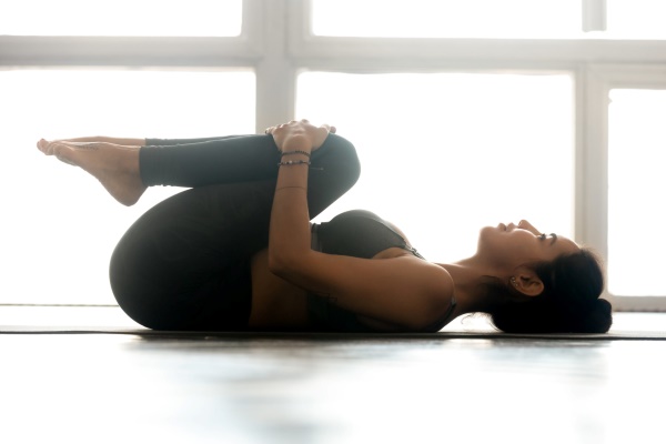woman do knees to chest pose hatha yoga