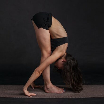 woman wear black yoga bending foward pose hatha yoga beginners