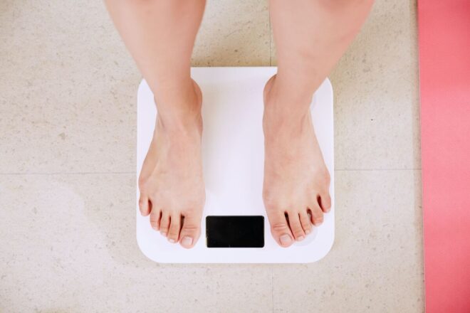 person on white scale measuring weight