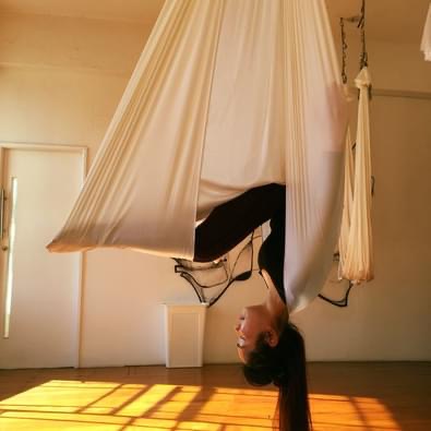 woman long hair doing aerial yoga in yoga studio sunshine