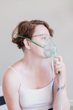 woman holding oxygen mask respiratory issue aerial yoga
