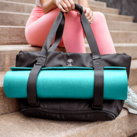 blue yoga mat on black warrior2 yoga bag girl sitting on stairs pink pants