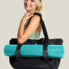 Blonde Girl smiling at camera carrying on shoulder warrior2 black yoga tote bag blue yoga mat