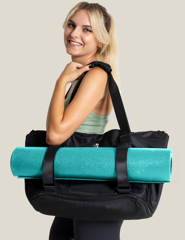 Blonde Girl smiling at camera carrying on shoulder warrior2 black yoga tote bag blue yoga mat