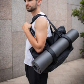 man in white singlet on the street carrying warrior2 yoga gym bag